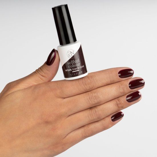 Hand met gelakte nagels en nagellakflesje. Opschrift: selfgel colour N°025 black rose STEP 03.