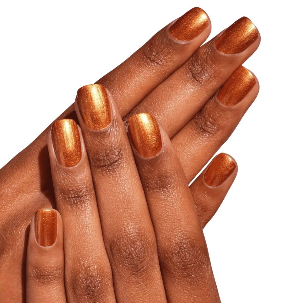 Mains avec ongles vernis dorés. Teint foncé. Surface brillante.