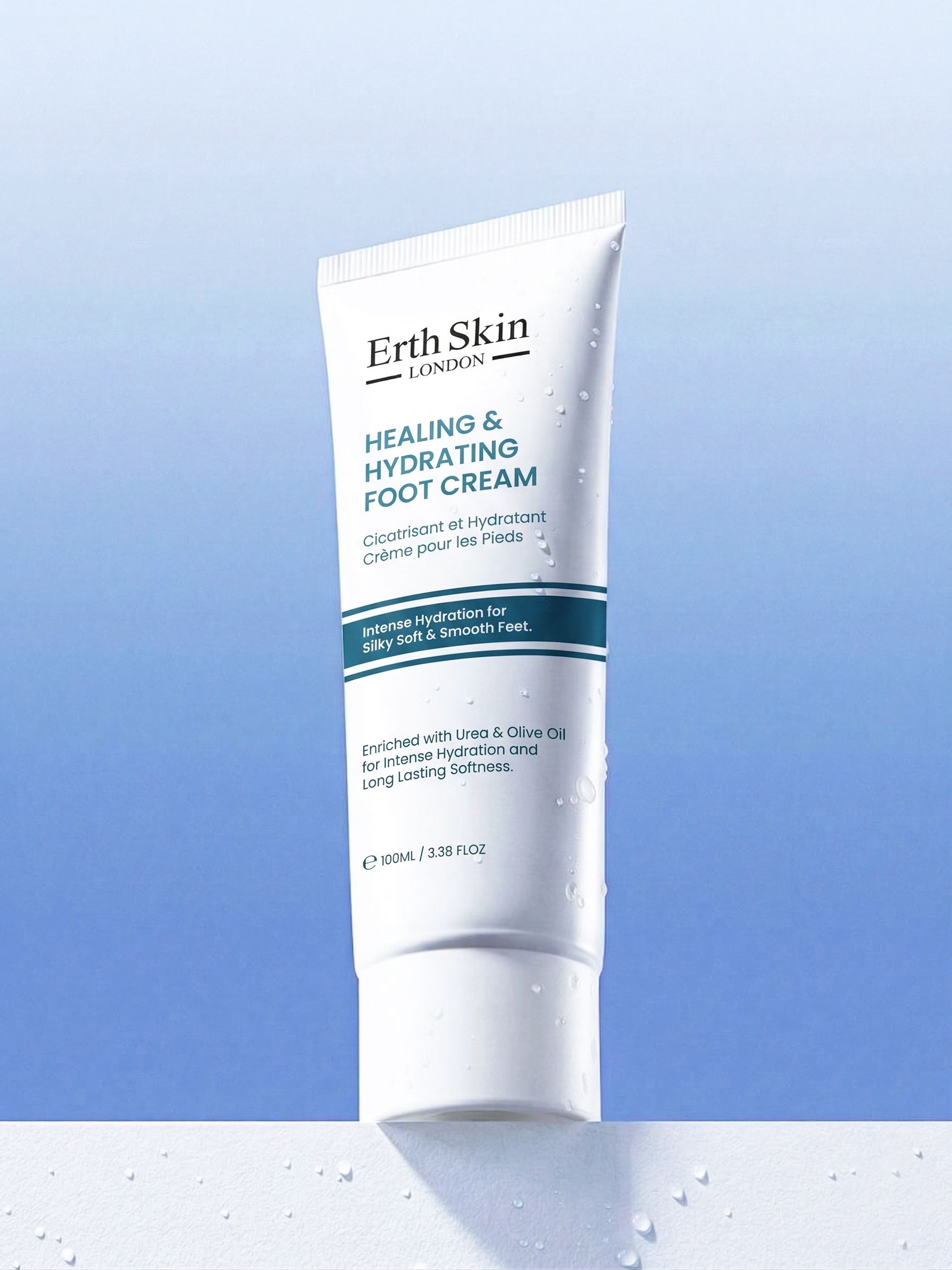 Witte tube Erth Skin London Helende en hydraterende voetcrème op blauwe achtergrond met waterdruppels.