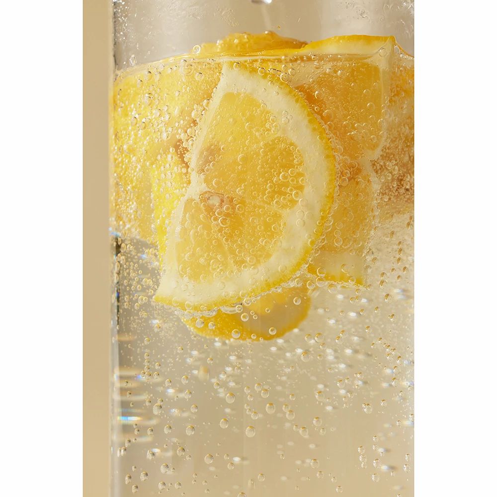 Verre contenant un liquide jaune et des tranches de citron. Bulles dans le verre.