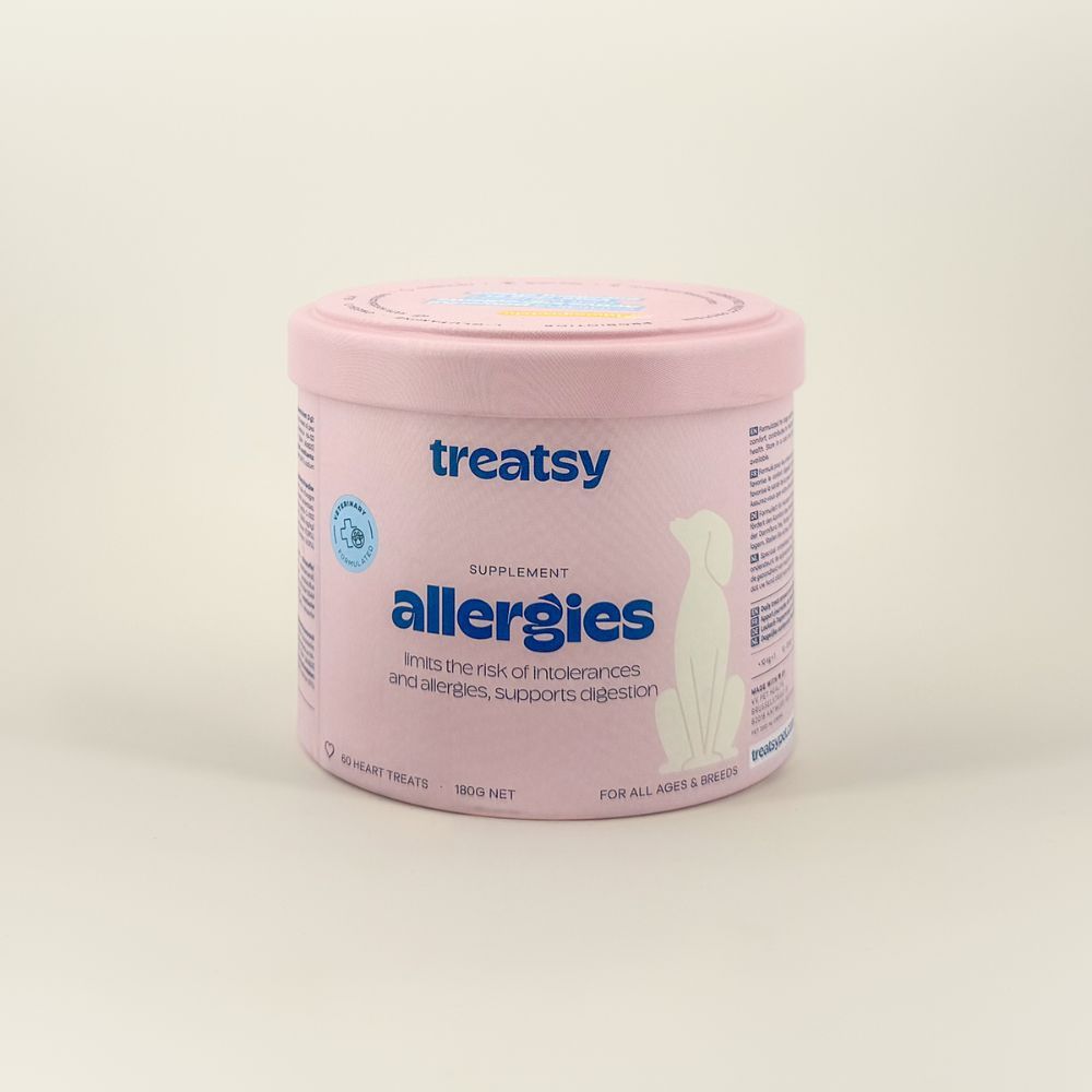 Boîte rose avec "Treatsy Allergies". Chien blanc sur boîte. Texte : "180g NET".