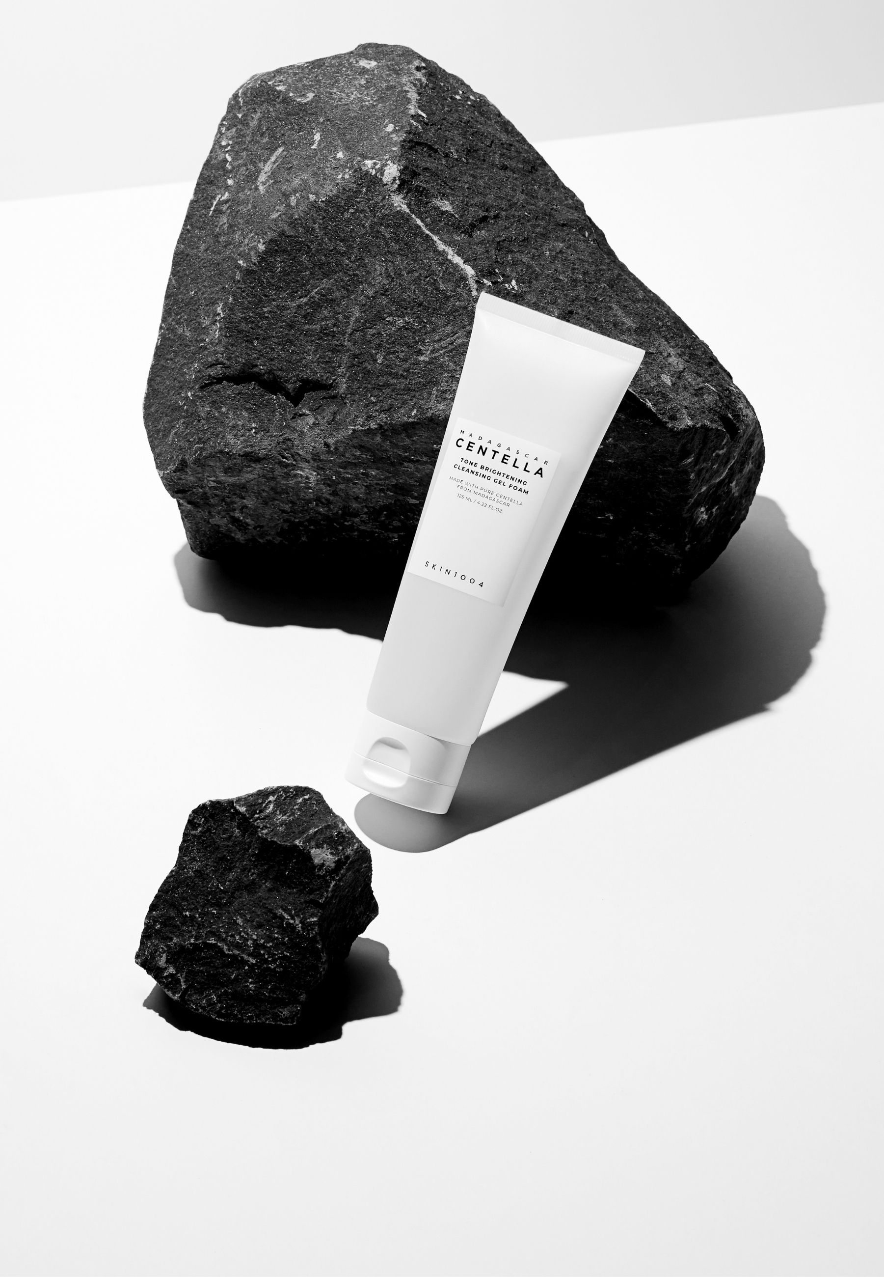 Tube blanc, pierres noires. Texte: MADAGASCAR CENTELLA, Tone Brightening Cleansing Gel Foam. Marque SKIN1004.