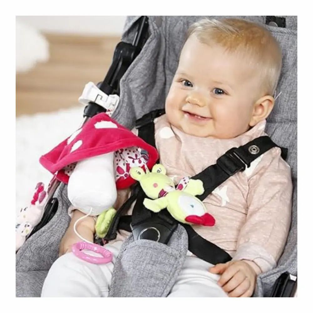 Bébé dans une poussette avec mobile. Mobile avec champignon, faon et grenouille. Bébé assis dans la poussette et souriant.