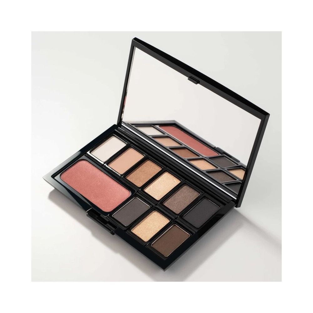 Boîte de beauté Magnum noire ouverte, avec miroir et fards à paupières et blush. Sur fond blanc.
