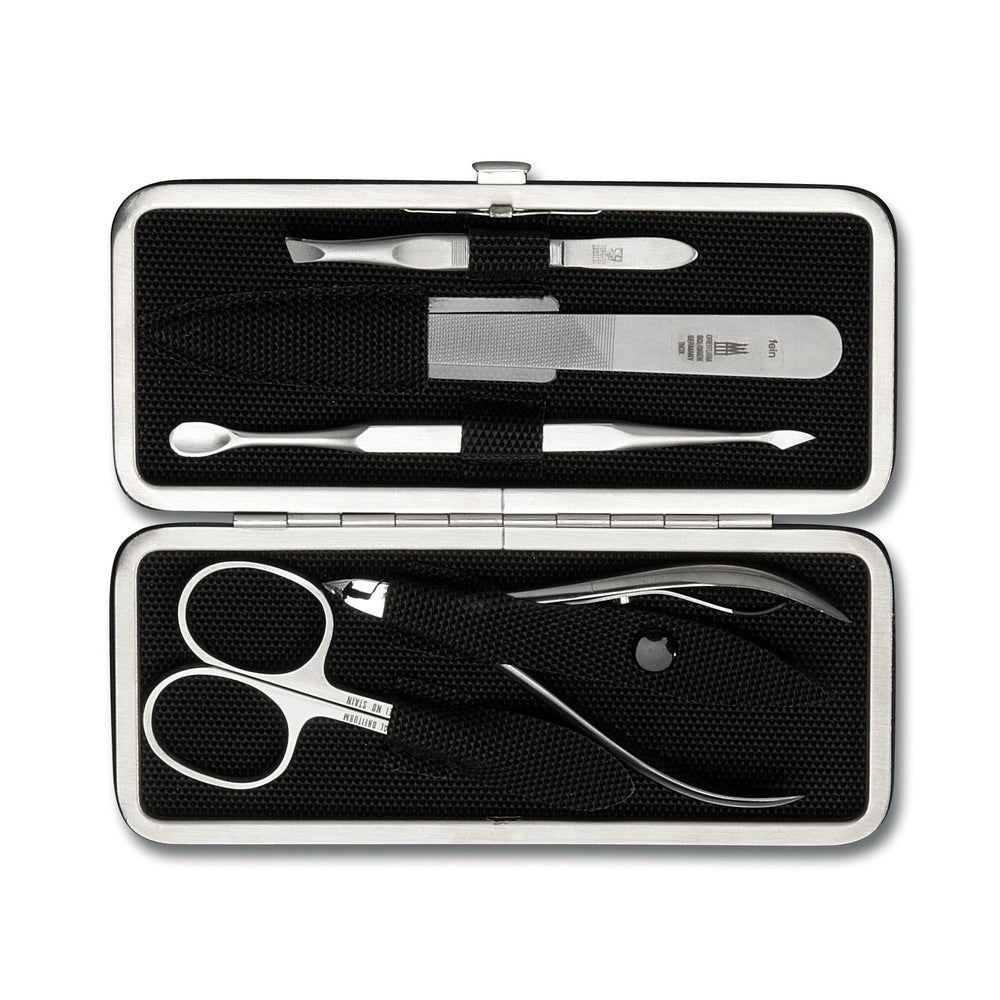 Coffret manucure en métal argenté. Ciseaux à ongles, lime, pince à épiler et autres outils. Intérieur noir.