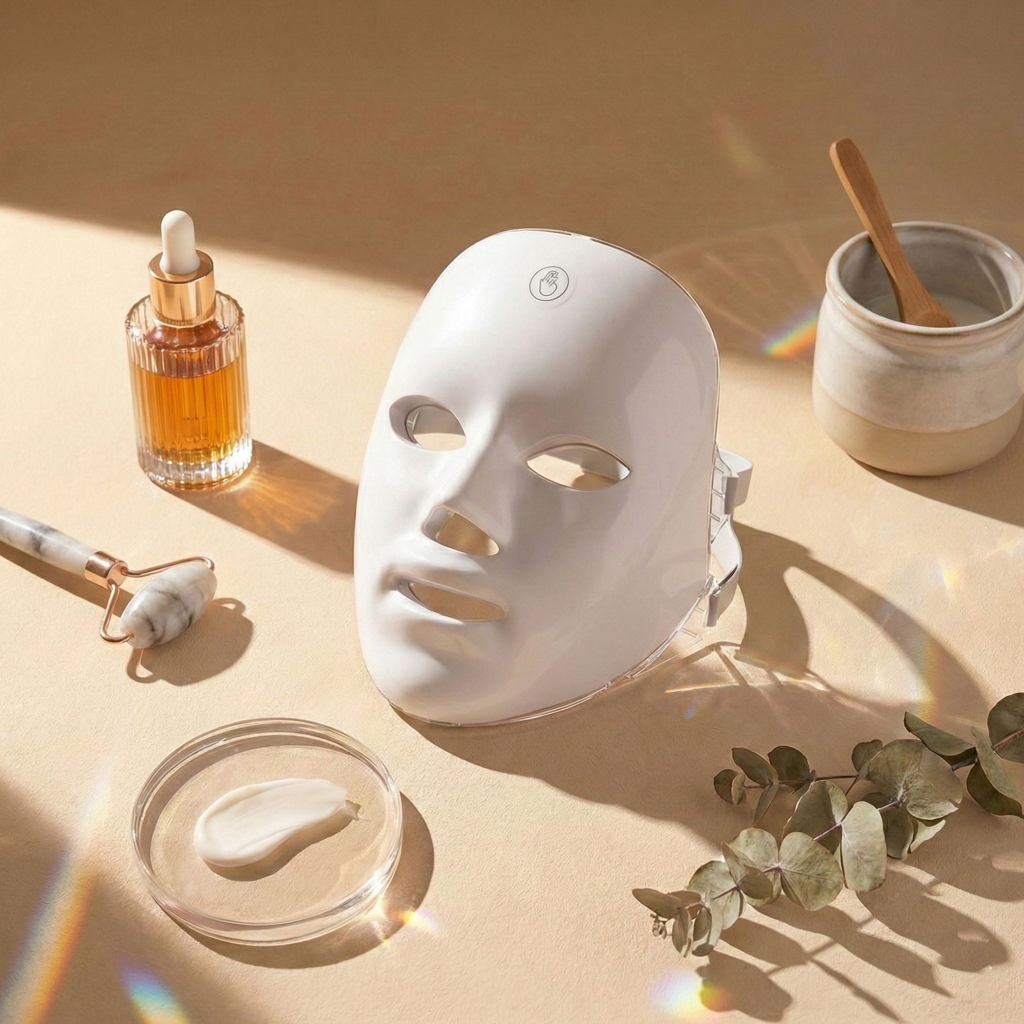 LED-lichttherapiemasker met huidverzorgingsproducten zoals serum en gezichtsroller.