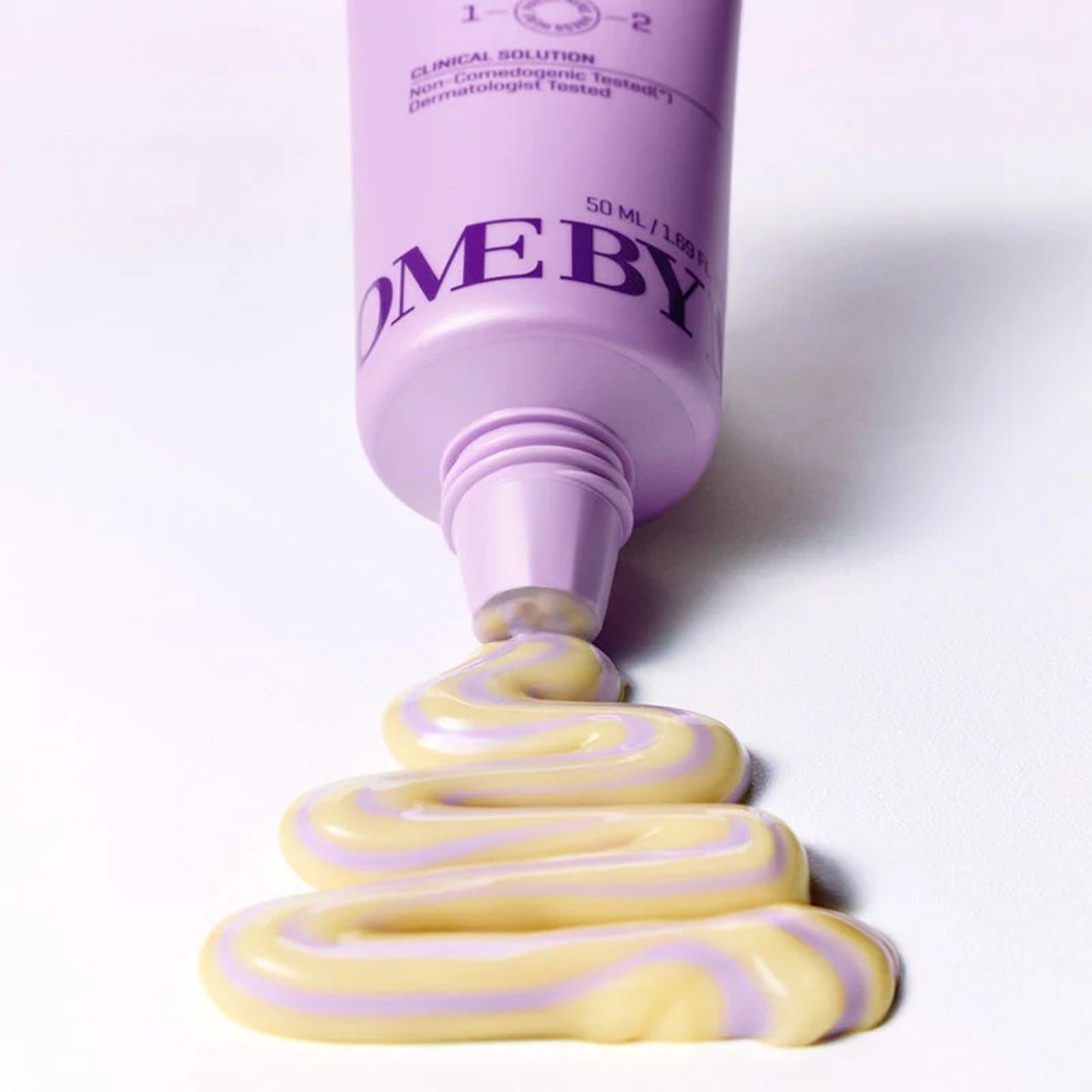 Tube violet de Retinol Bakuchiol Dual Cream d'où s'écoule une crème bicolore en serpentin.