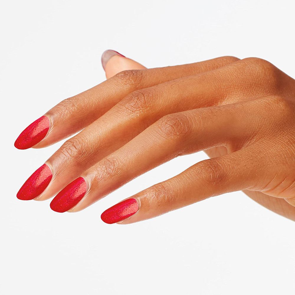 Main avec ongles vernis. Vernis à ongles rouge pailleté.