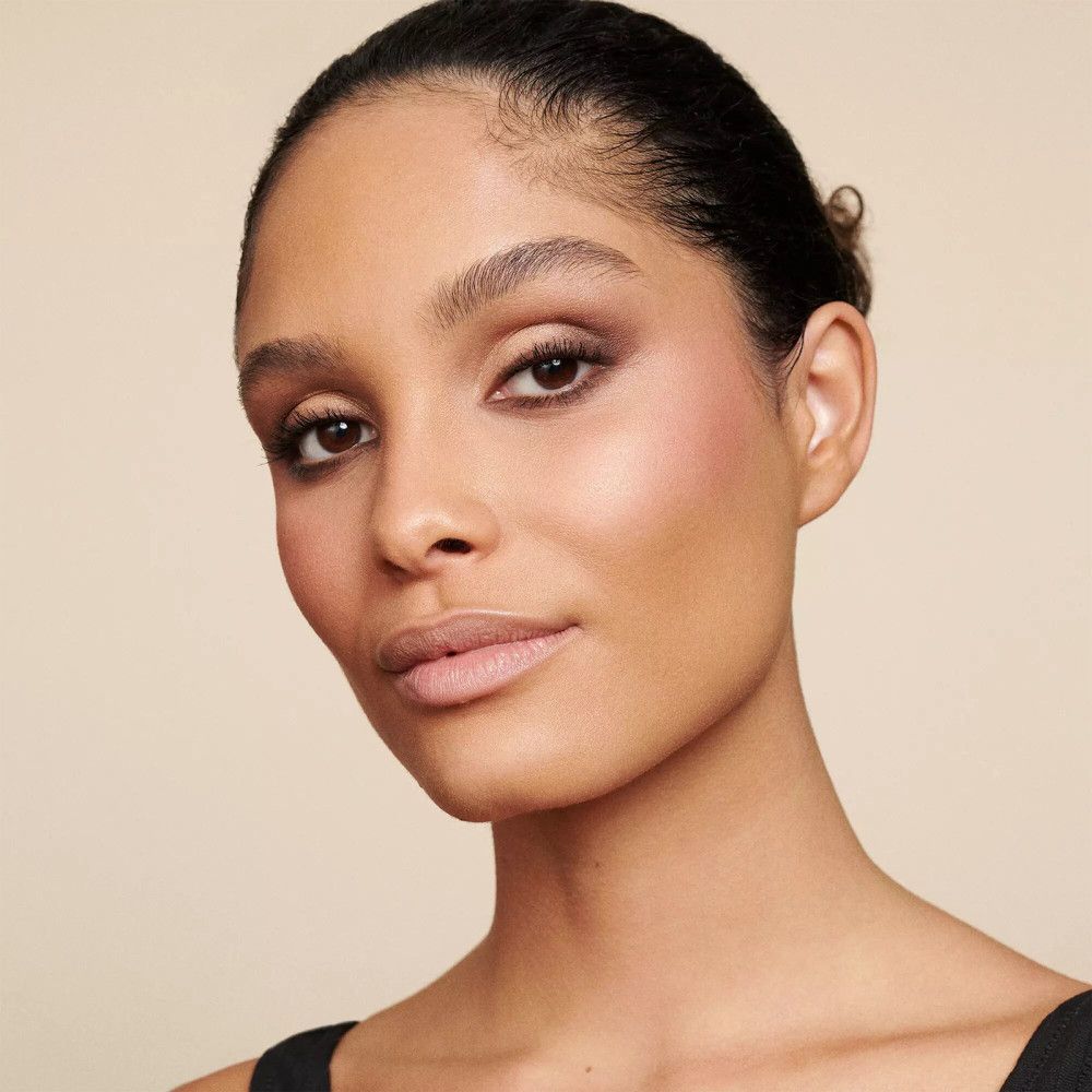 Close-up van een vrouw met make-up. Ze draagt nude oogschaduw en heeft een natuurlijke teint. Zwarte top.