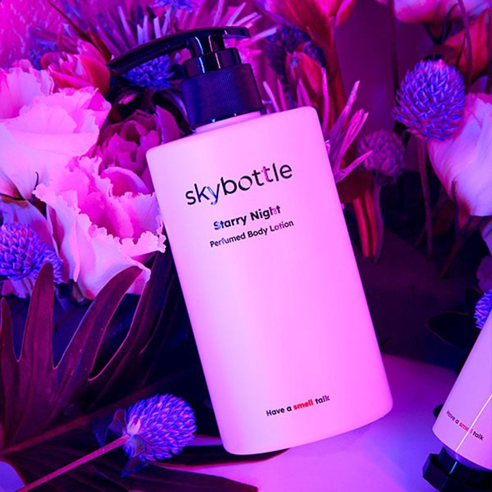 Witte fles met zwarte pomp, omringd door bloemen. Opschrift: skybottle, Starry Night, Perfumed Body Lotion.