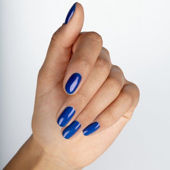 Main avec ongles vernis en bleu. Tous les ongles sont recouverts de vernis à ongles bleu.