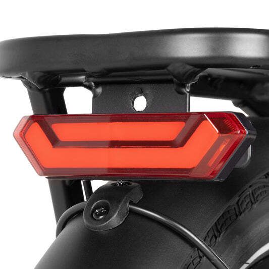 Achterlicht op een fiets. Rood licht. Zwarte bagagedrager en spatbord.