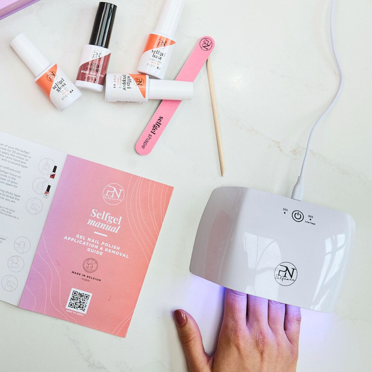 Kit manucure avec lampe UV, brochure, lime et flacons. Inscription: selfgel manual. Logo PN.