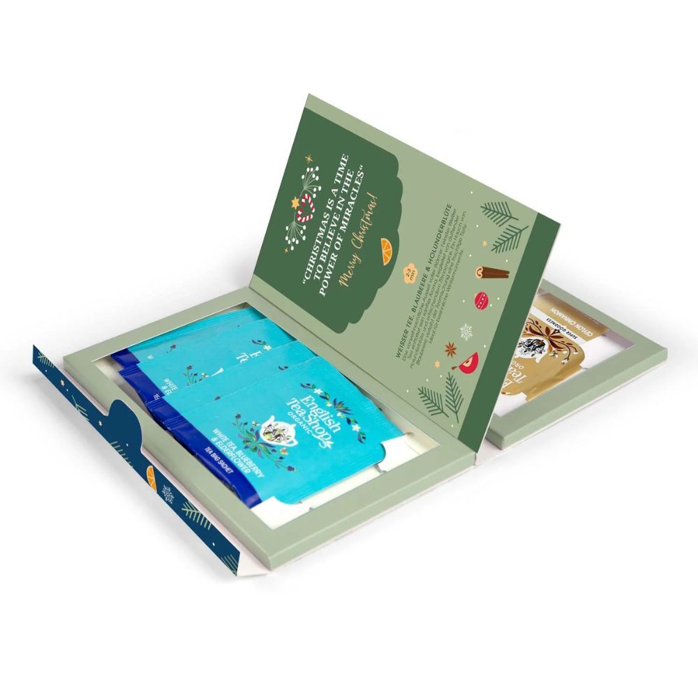Open geschenkverpakking met blauwe theezakjes. Opschrift: English Tea Shop. Groene binnenkant met kerstontwerp.