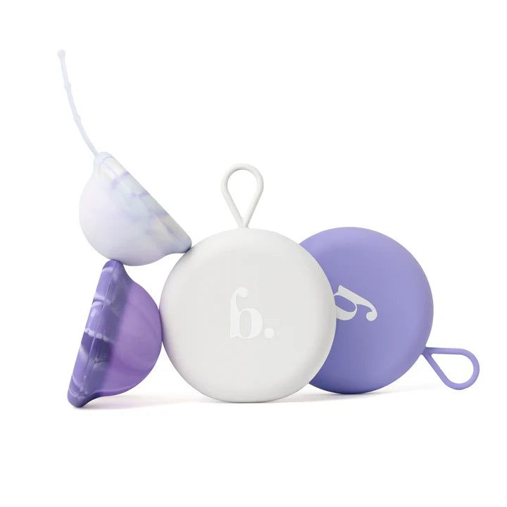 Verschillende menstruatiedisks in paars en wit. Eén disk is open, met een terugtrekkoord. Ronde containers met logo.