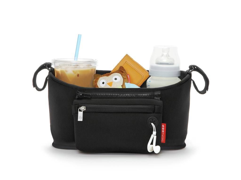 Organisateur de poussette noir avec contenu : boisson, jouet, biberon. Logo Skip Hop visible.