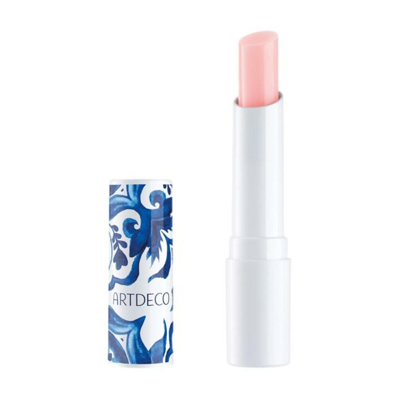 Stick de baume à lèvres blanc avec embout rose. À côté, l'étui à motifs bleus et blancs avec le texte ARTDECO.