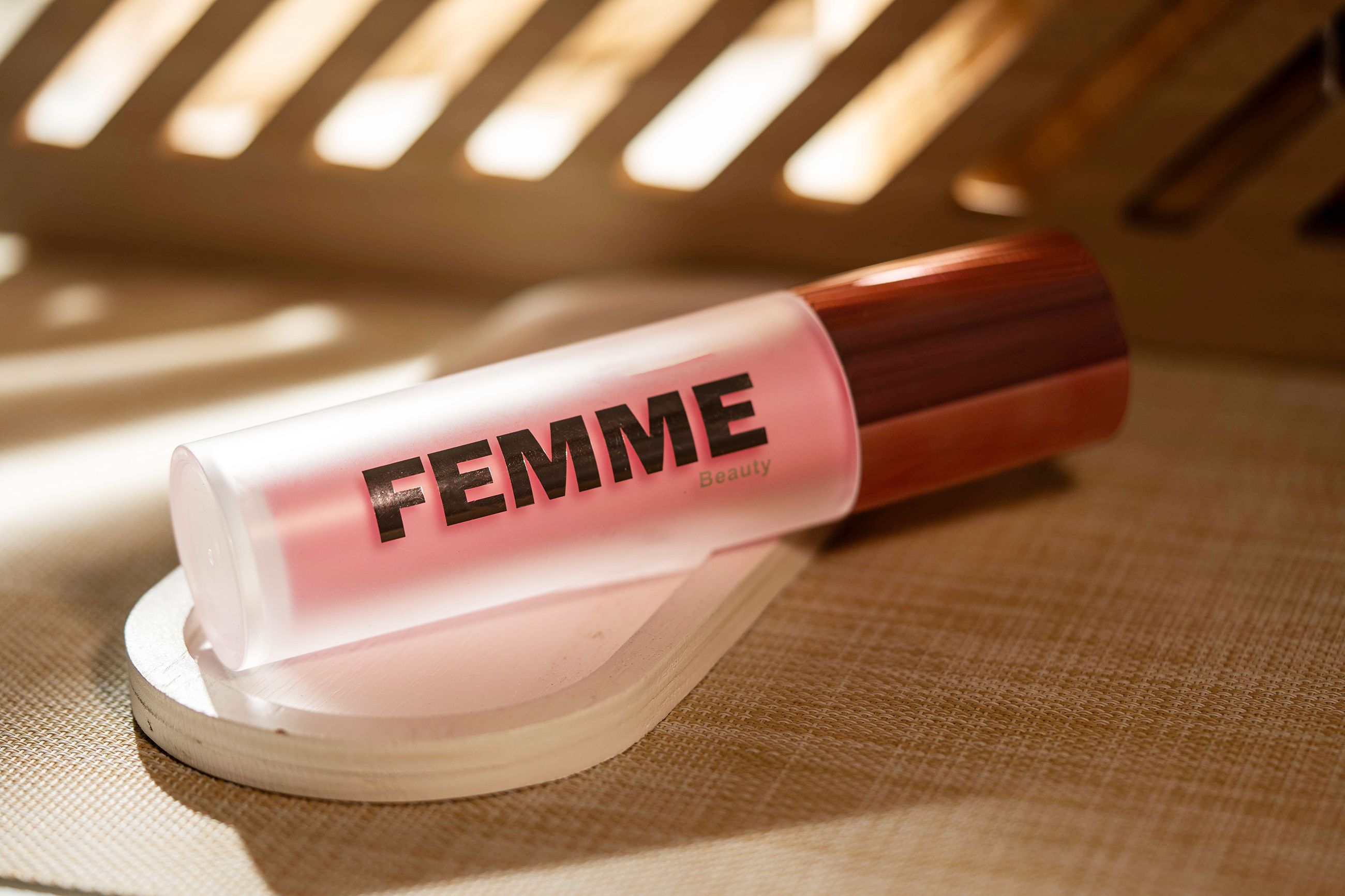 Liggende fles met matte afwerking en roze inhoud, roségouden dop. Merk: FEMME Beauty.