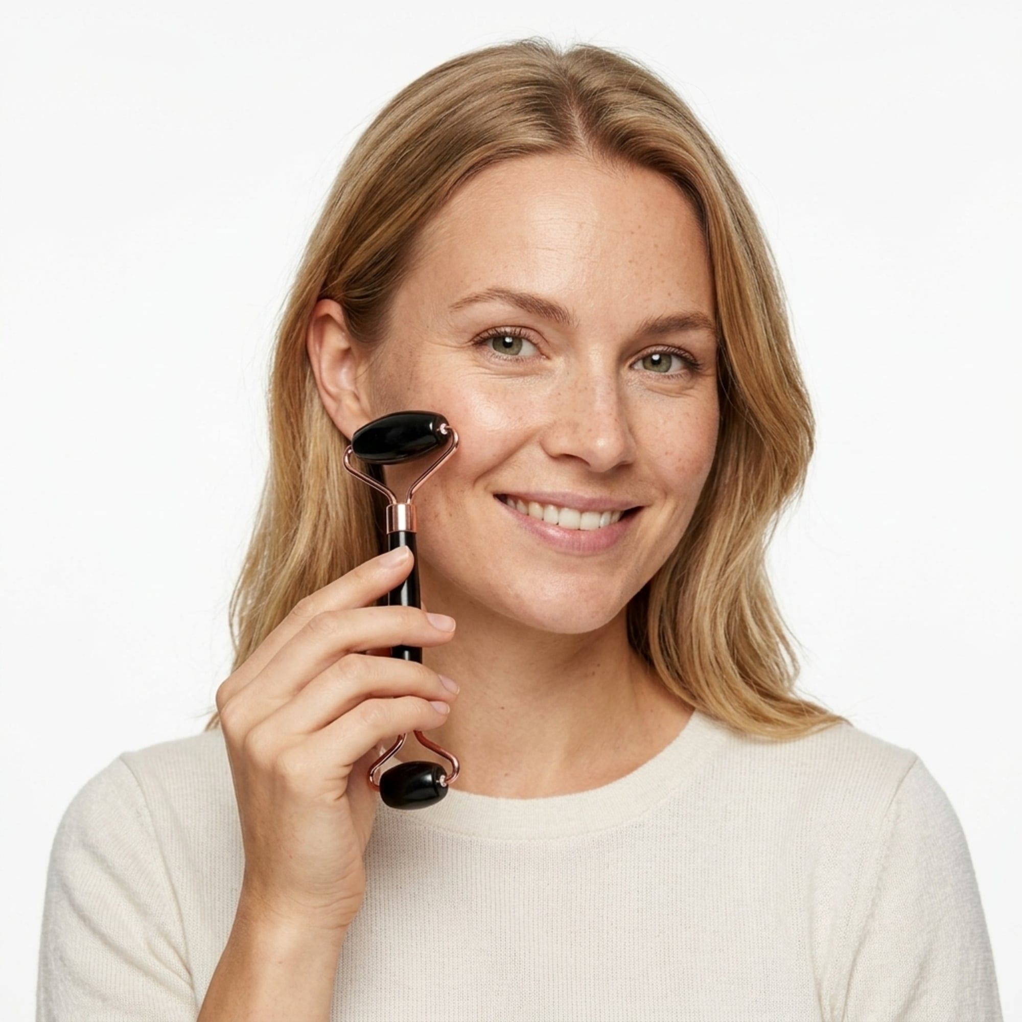 Vrouw met een zwarte jade roller op haar gezicht, lachend.