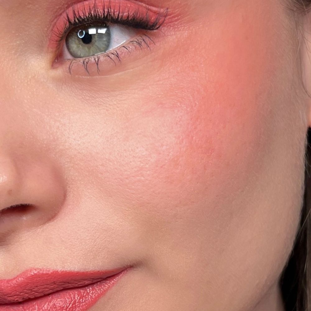 Close-up van een oog met roze oogschaduw, blush en lippenstift. Groene ogen.