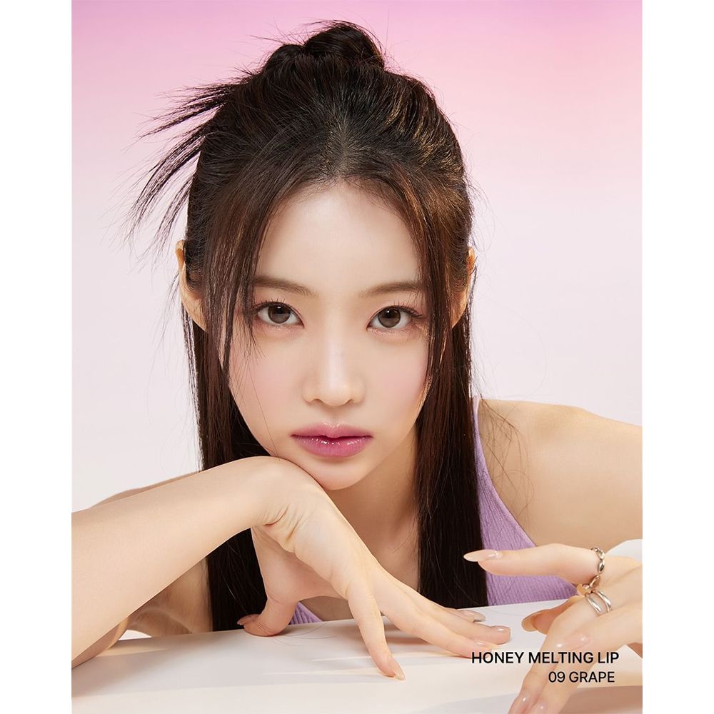 Portrait d'une femme avec Honey Melting Lip Gloss 09 Grape. Rouge à lèvres sur les lèvres. Texte: HONEY MELTING LIP 09 GRAPE.