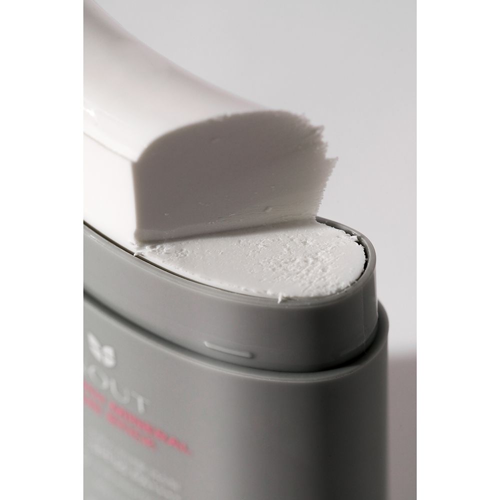 Close-up van de zonnebrandstick. Wit product zichtbaar. Grijze houder met witte dop.