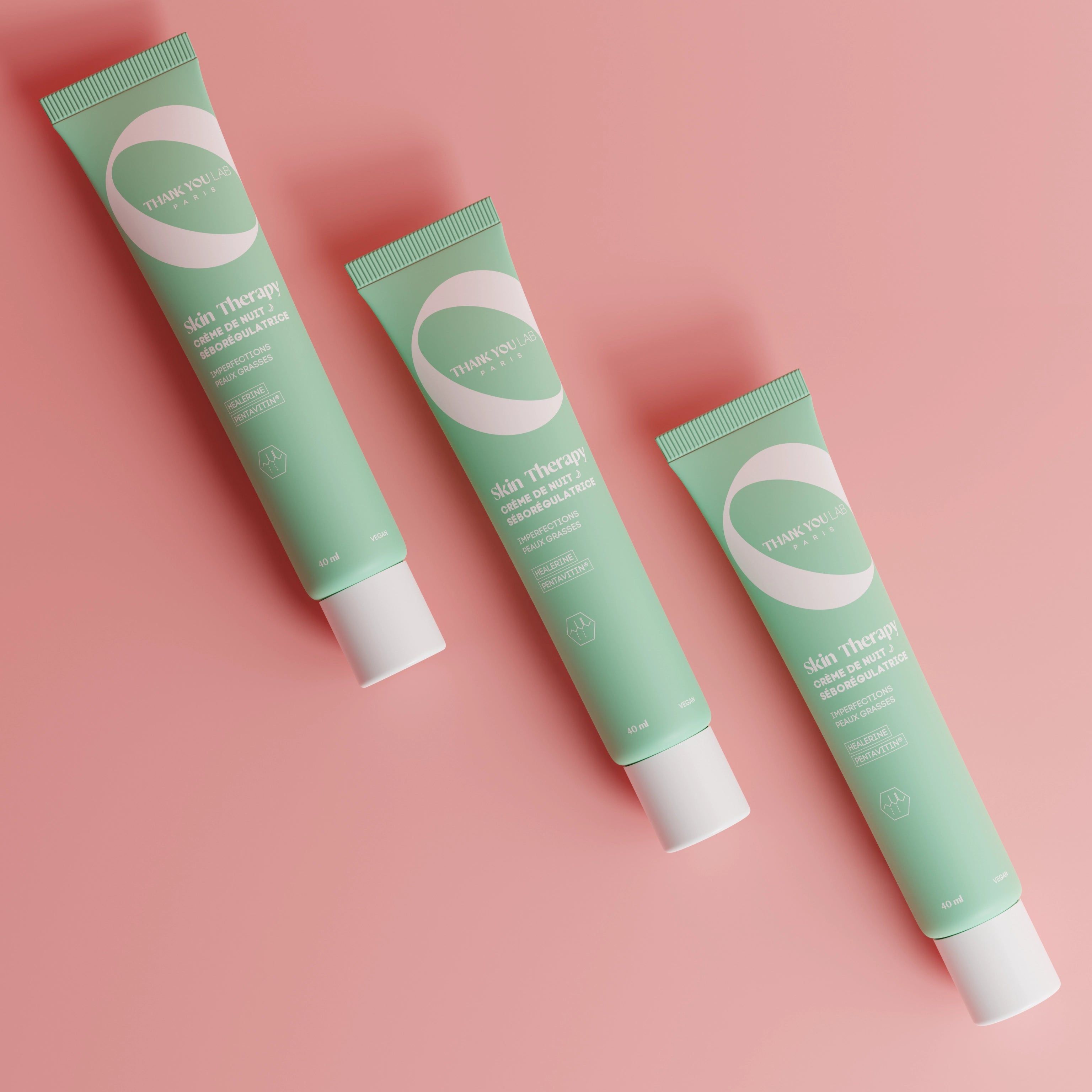 Trois tubes verts sur fond rose. Inscription: Skin Therapy, Crema notte. Bouchon blanc.