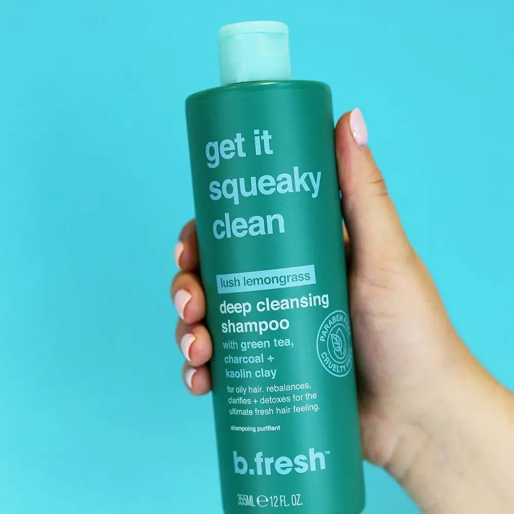 Groene shampoo fles, vastgehouden door een hand. Tekst: Get it squeaky clean, deep cleansing shampoo. Bevat groene thee, houtskool en kaolienklei.