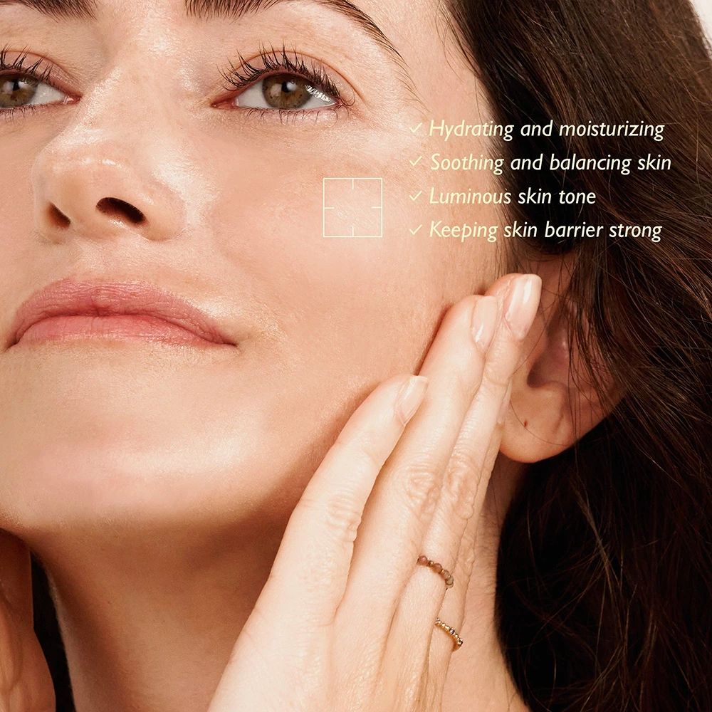 Vrouw raakt haar gezicht aan. Tekst: Hydraterend, kalmerend, stralende teint, sterke huidbarrière.