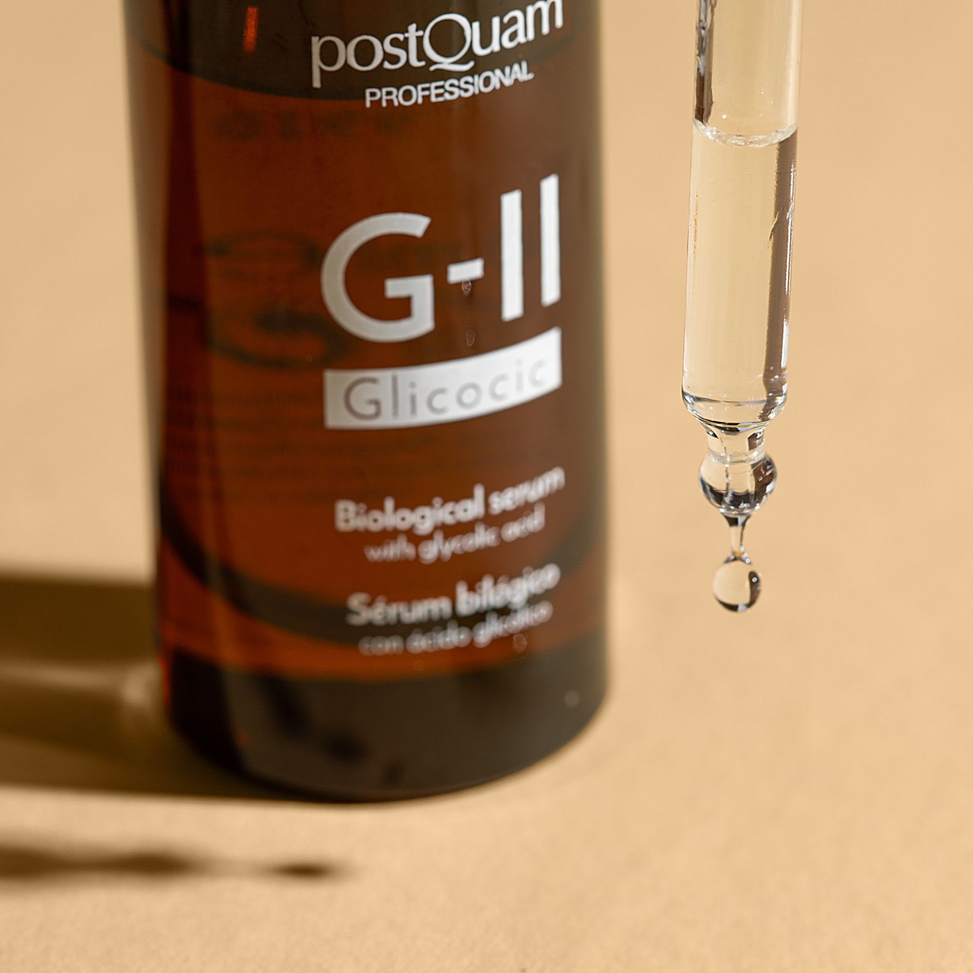 Close-up van een serumfles met druppelaar. Druppel serum aan het einde van de druppelaar. Opschrift: PostQuam Professional, G-II Glicolic.