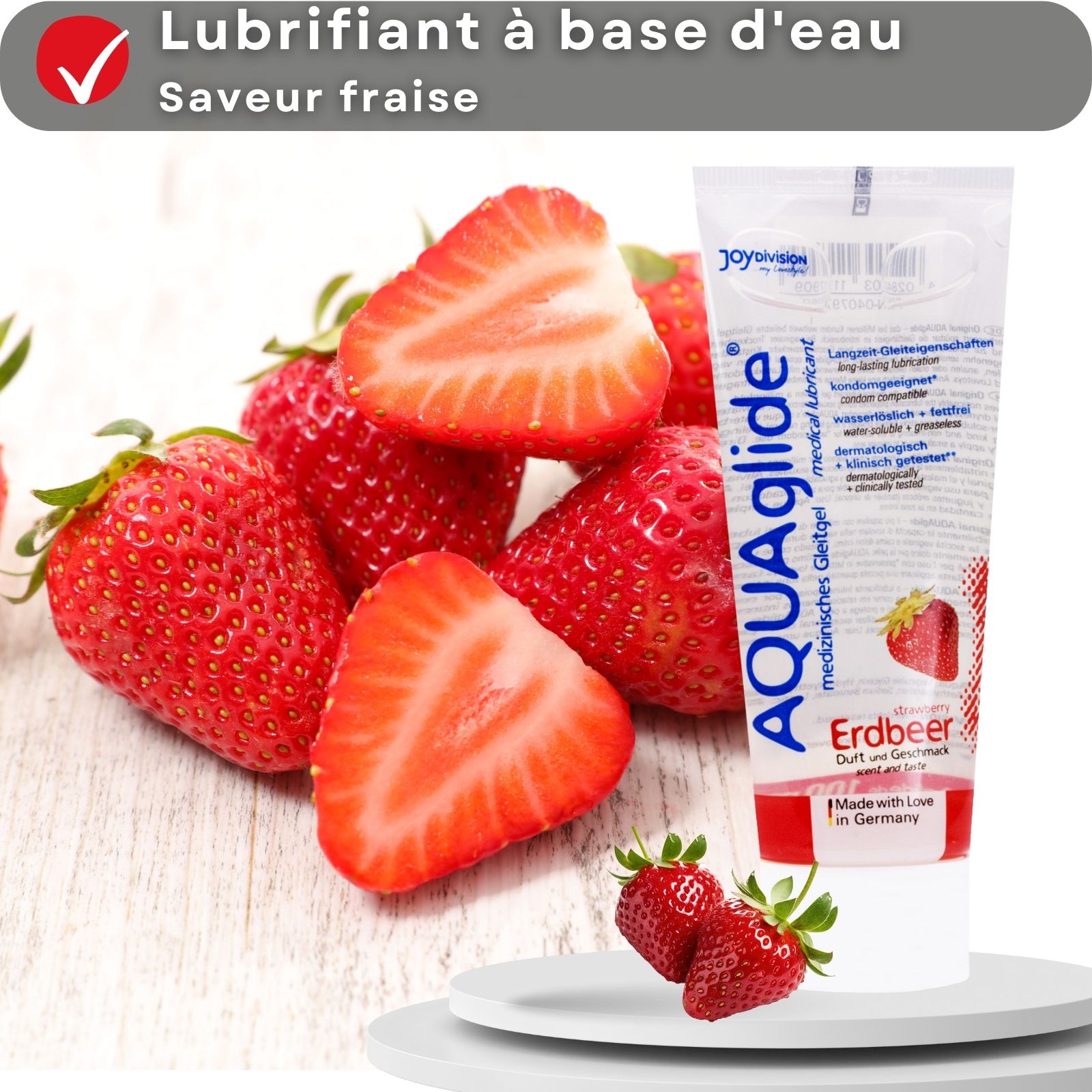Tube de gel AQUAglide fraise. À base d'eau, saveur fraise. Fraises sur fond en bois.