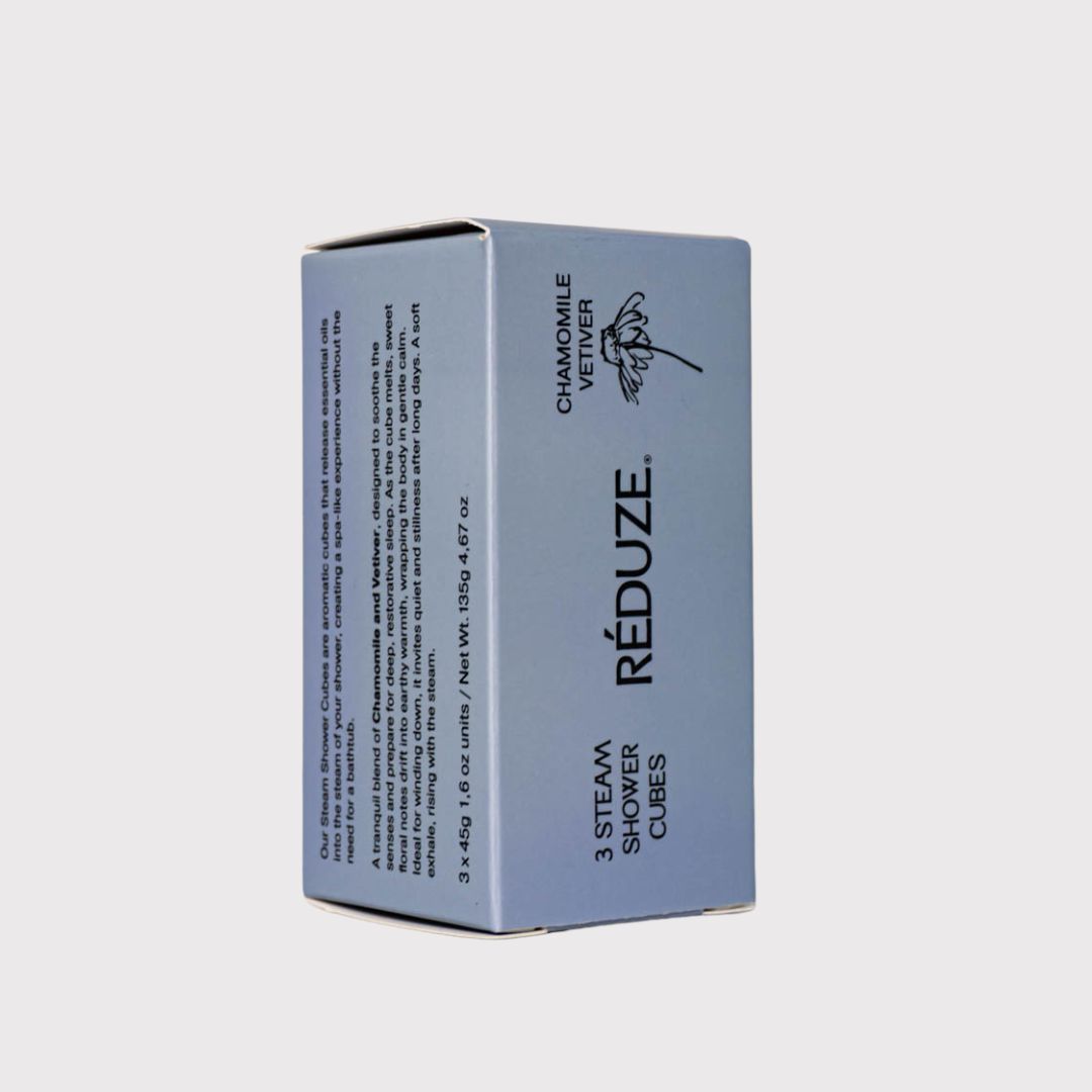 Een blauwe doos met RÉDUZE, Kamille & Vetiver en 3 Steam Shower Cubes. Vierkante vorm.