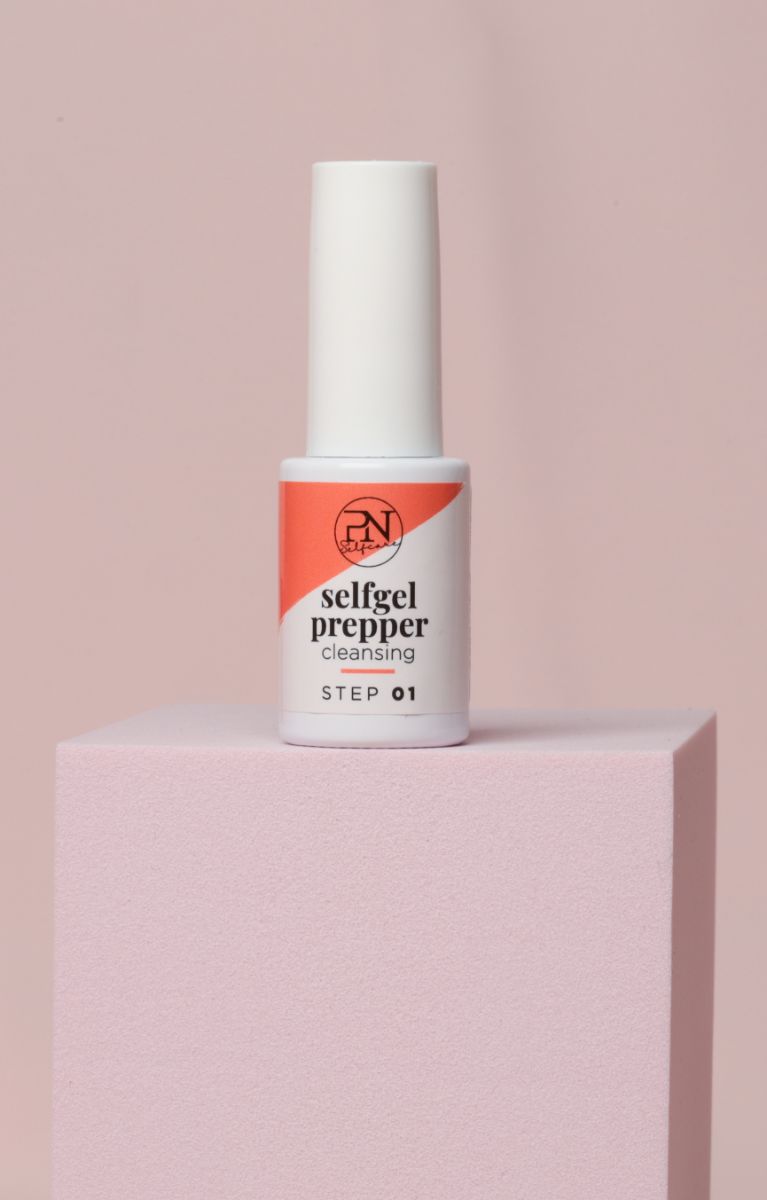 Flacon avec bouchon blanc. Étiquette avec logo PN, texte "selfgel prepper cleansing" et "STEP 01". Sur socle rose.