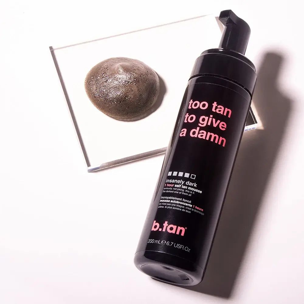 Flacon noir avec pompe. À côté, une goutte d'autobronzant sur une plaque de verre.