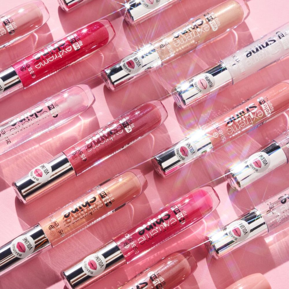 Meerdere Essence Extreme Shine Volume lipgloss tubes op roze achtergrond. Verschillende kleuren.