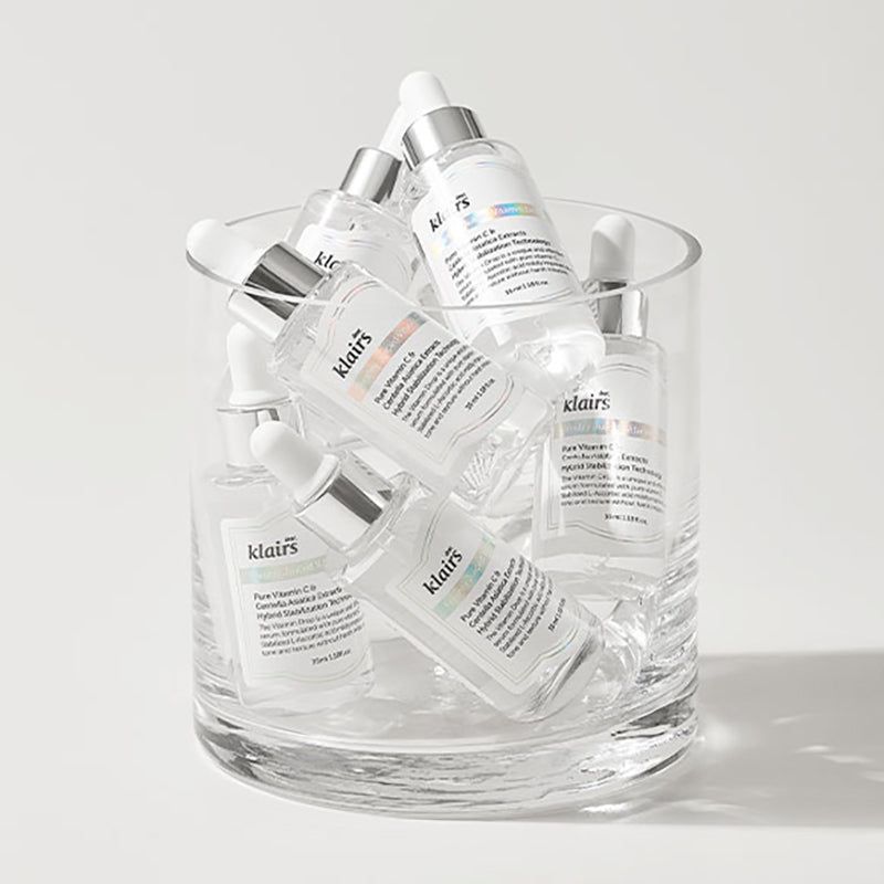 Plusieurs flacons de sérum dans un récipient en verre. Klairs Freshly Juiced Vitamin Drop. Flacons avec pipettes, étiquettes.