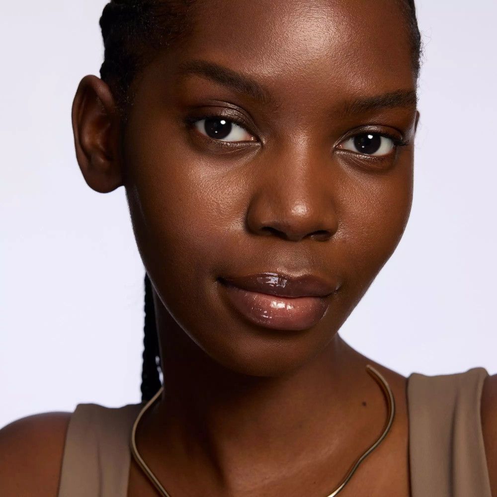 Close-up van een vrouw met getinte lippen. Ze draagt een gouden halsketting.