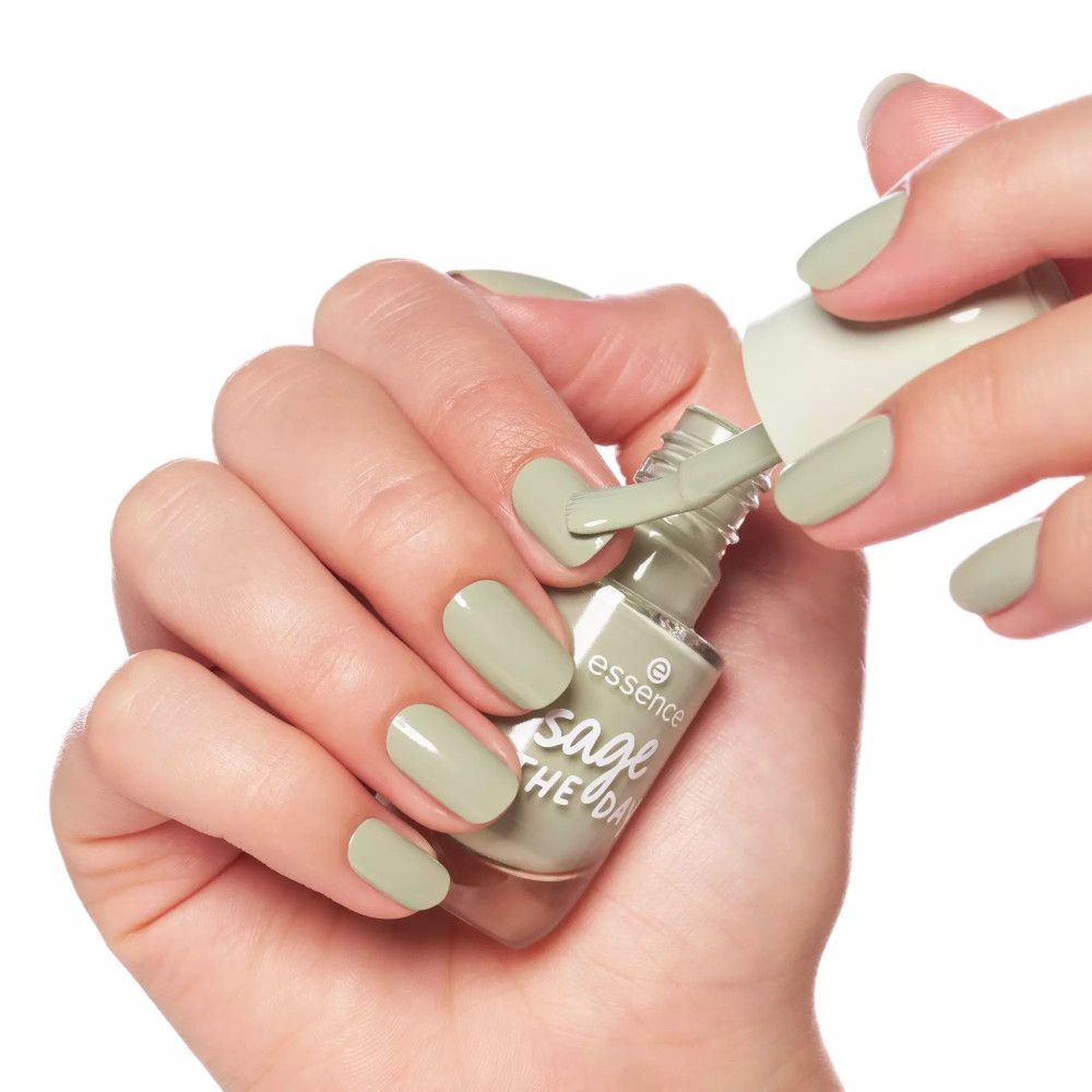 Main vernissant les ongles avec du vernis vert clair. On peut lire "essence sage THE DAY" sur le flacon.