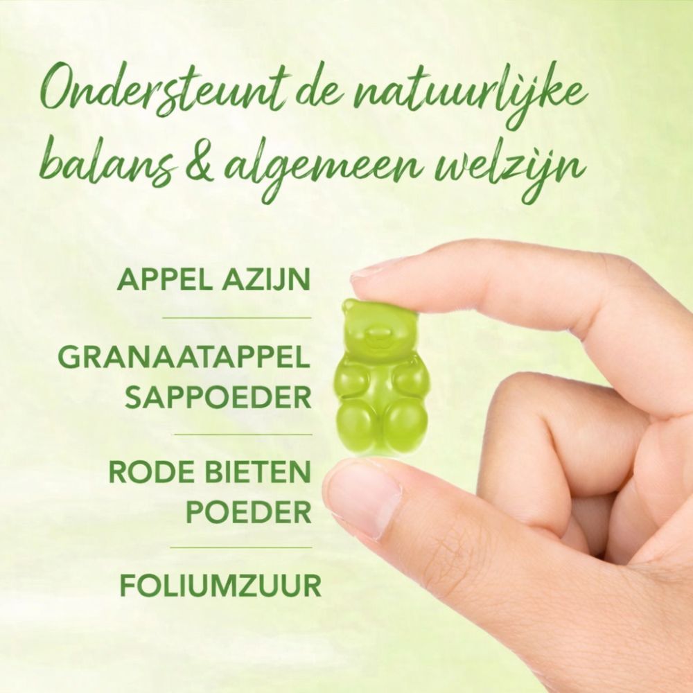 Hand houdt groene gummybeer vast. Tekst: Appelazijn, Granaatappelsappoeder, Rode bietenpoeder, Foliumzuur.