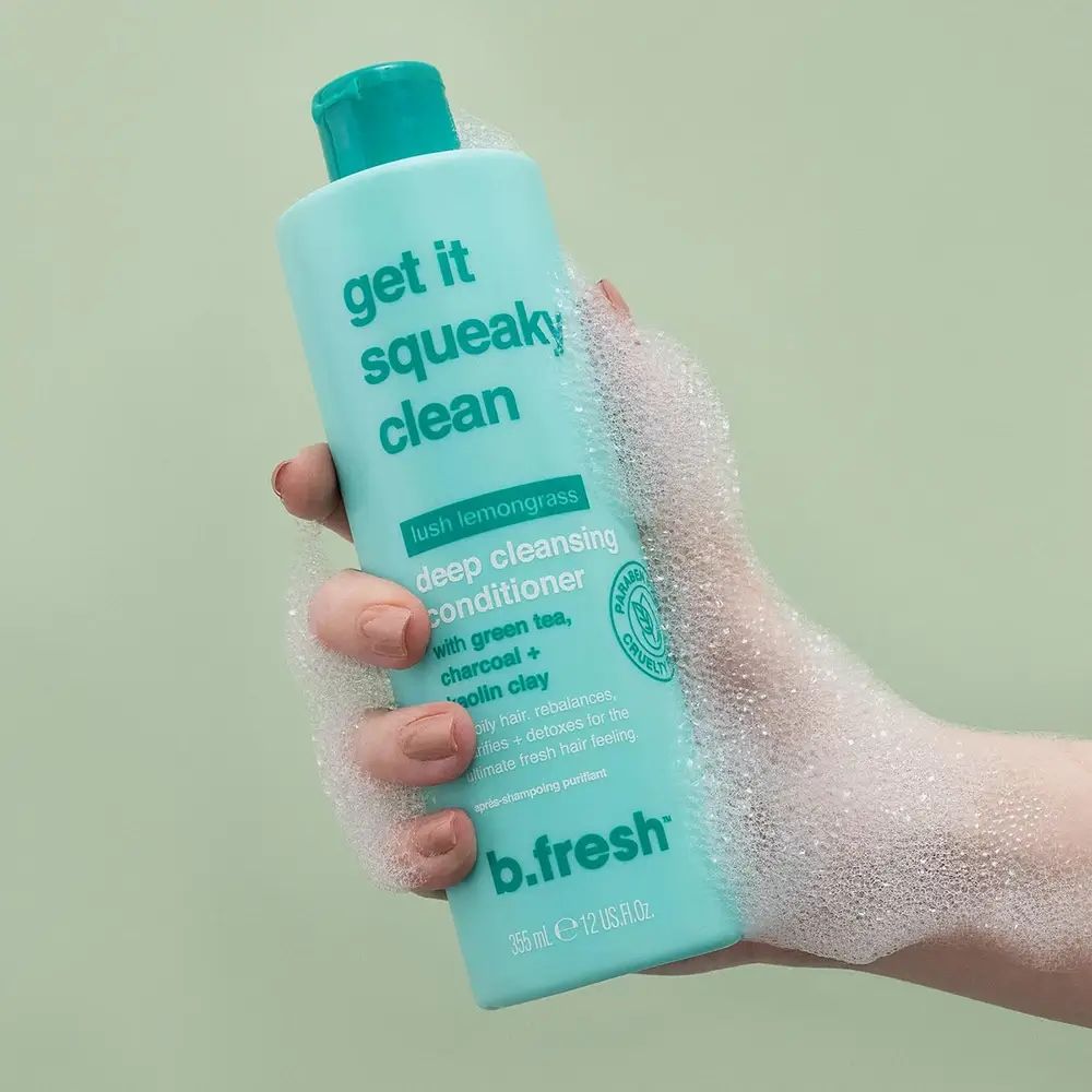 Turquoise fles met groene dop, vastgehouden door een hand met zeepschuim. Opschrift: Get it Squeaky Clean, b.fresh.