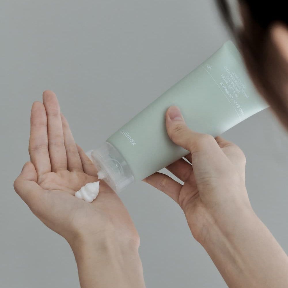 Eén hand knijpt Celimax Ji Woo Gae Cica BHA acne reinigingsschuim in de andere hand.