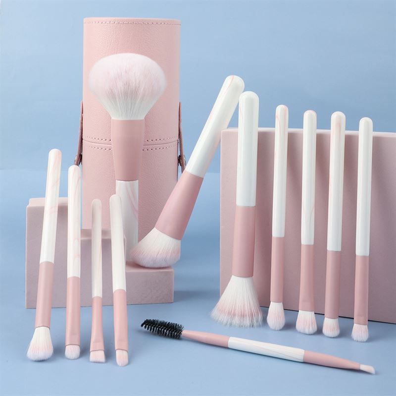 Ensemble de pinceaux de maquillage avec étui rose. Pinceaux avec manches roses et blancs. Différentes formes et tailles. Comprend également une brosse à cils.