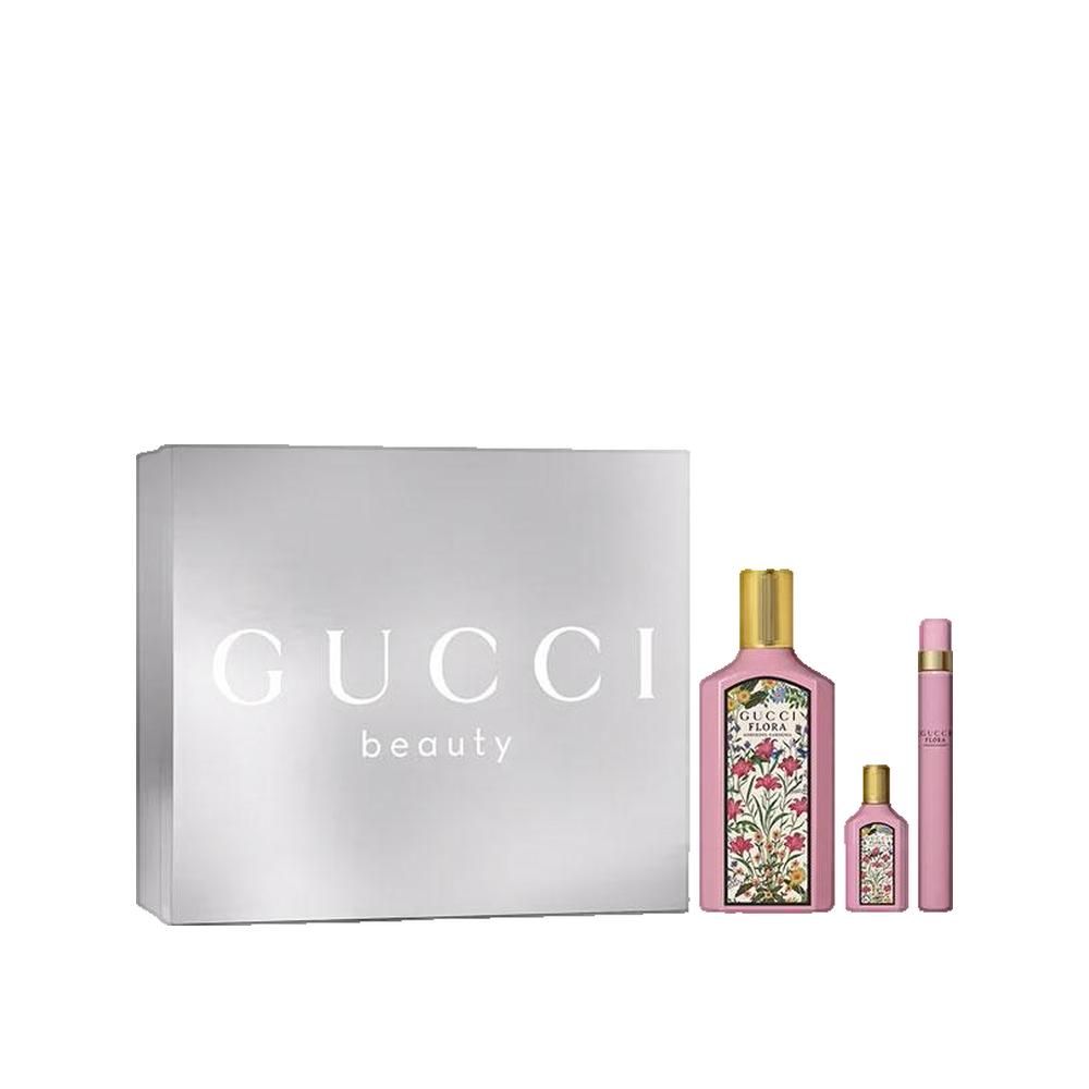 Coffret cadeau Gucci avec flacon, miniature et vaporisateur. Boîte argentée avec logo Gucci. Flacons roses, motifs floraux et bouchons dorés.