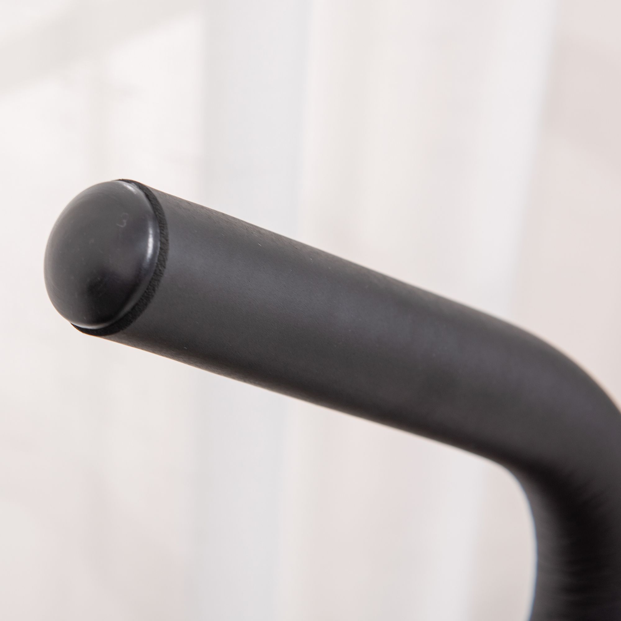 Close-up van de zwarte handgreep van een stepper. Ronde vorm, glad oppervlak.