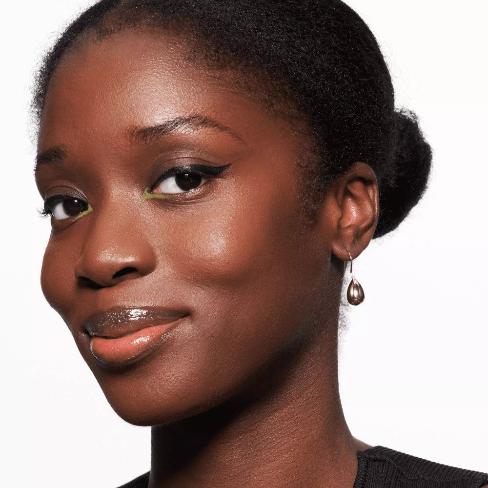 Portrait d'une femme avec eye-liner. Elle porte un chignon et des boucles d'oreilles.