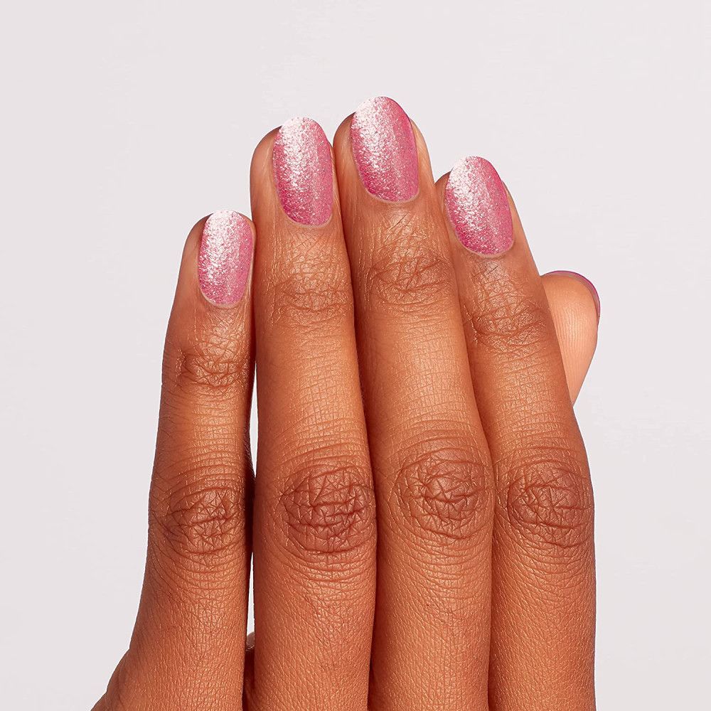 Main avec ongles vernis. Vernis à ongles rose pailleté.