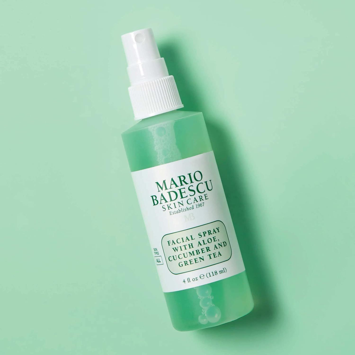 Mario Badescu gezichtsspray met aloë, komkommer en groene thee op groene achtergrond.