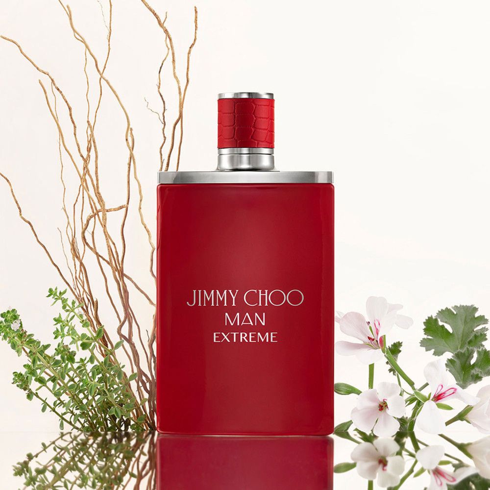 Flacon rouge avec bouchon argenté. Inscription : Jimmy Choo Man Extreme. Décoré de branches et de fleurs.