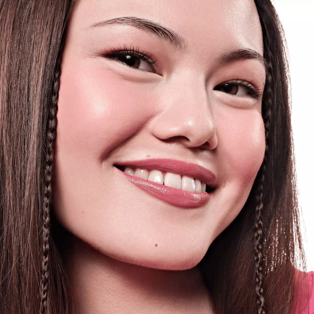 Portrait d'une femme avec du rouge à lèvres rose. Elle sourit.