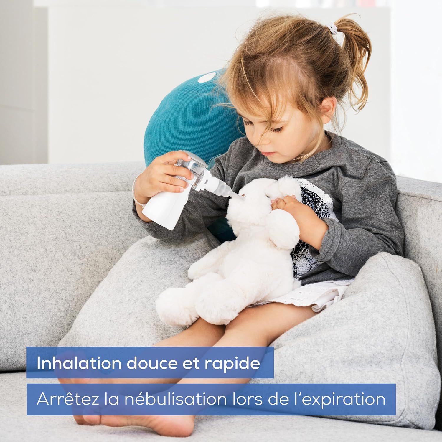 Une petite fille tient un nébuliseur près d'une peluche.